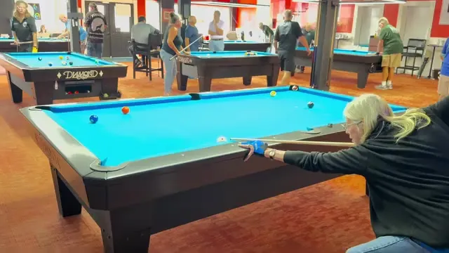 Woman enjoying a game on a Diamond billiards table with other players nearby